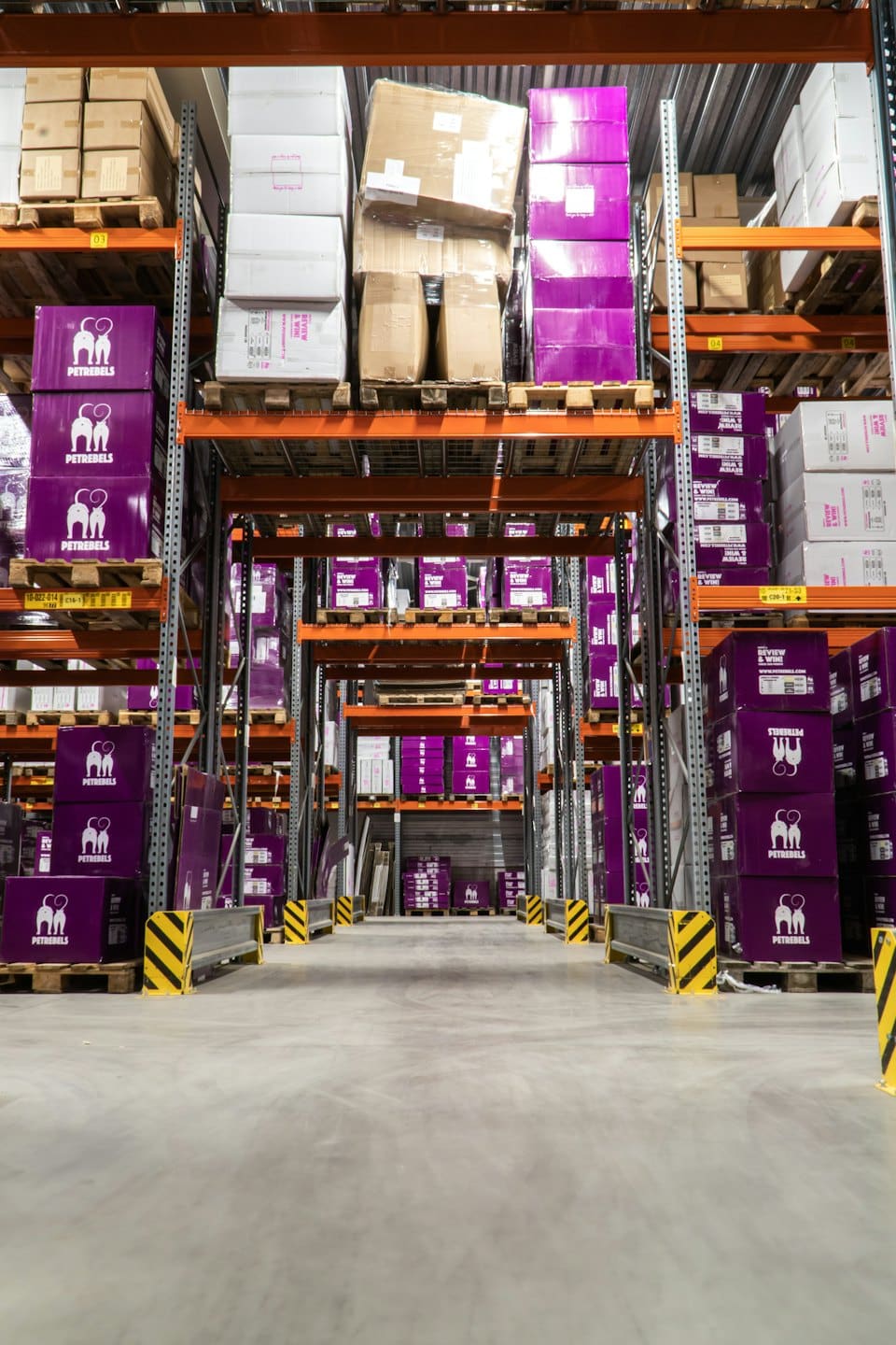 Warehouse aisle stacked high with purple and brown product boxes.