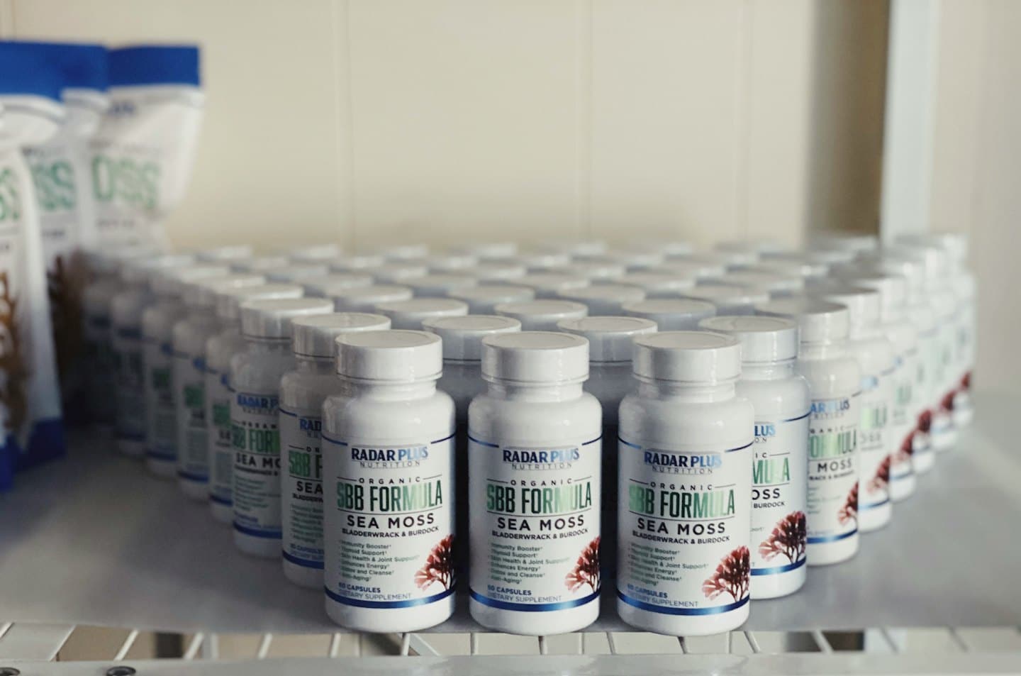 White supplement bottles are neatly arranged on a shelf.