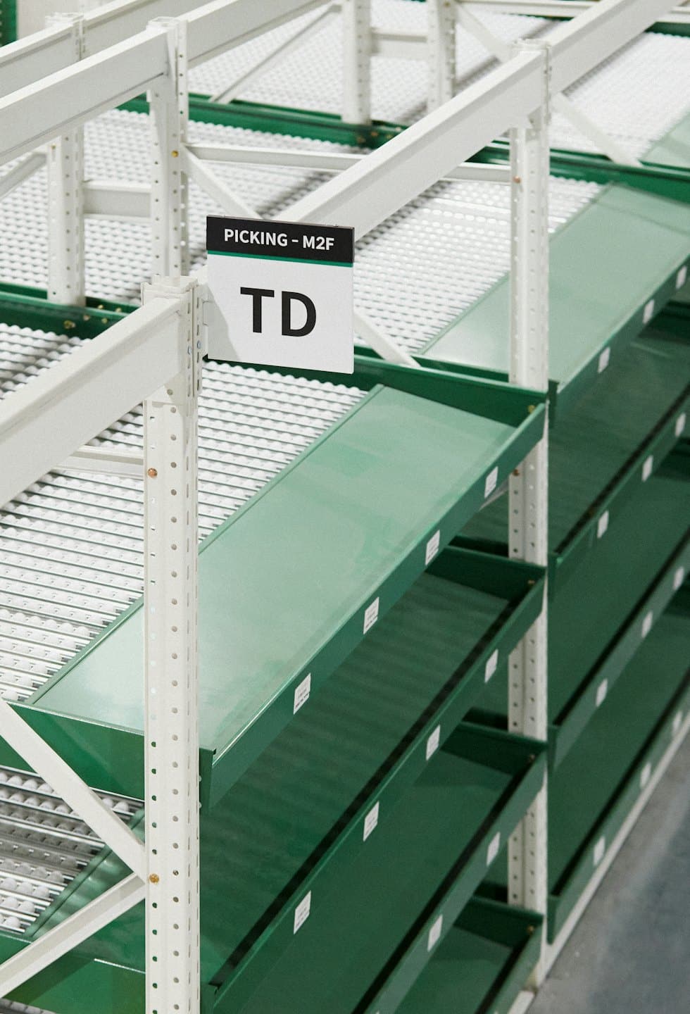 Rows of organized industrial shelving with green flow racks.