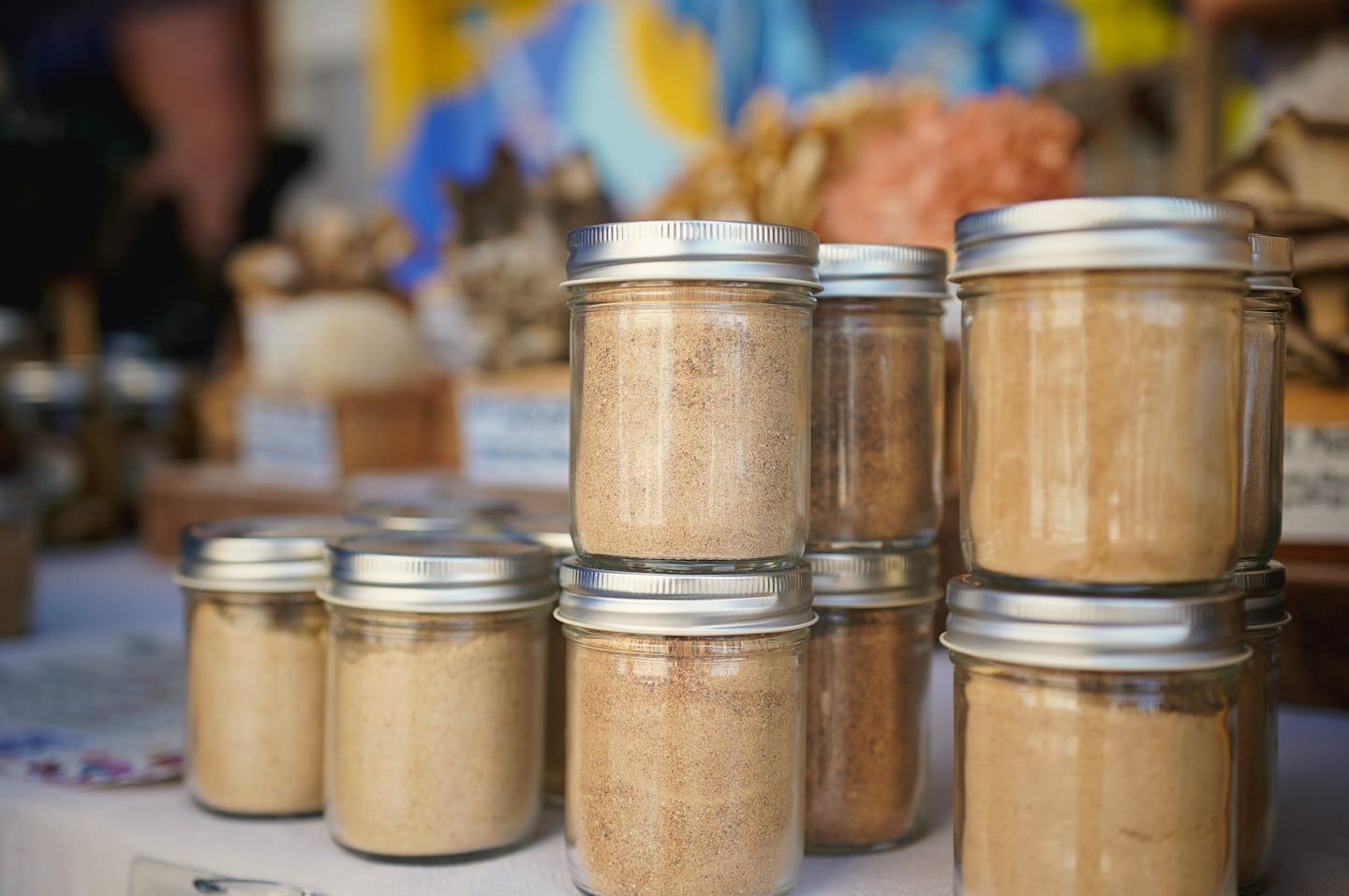 Glass jars filled with spices arranged on a white table.